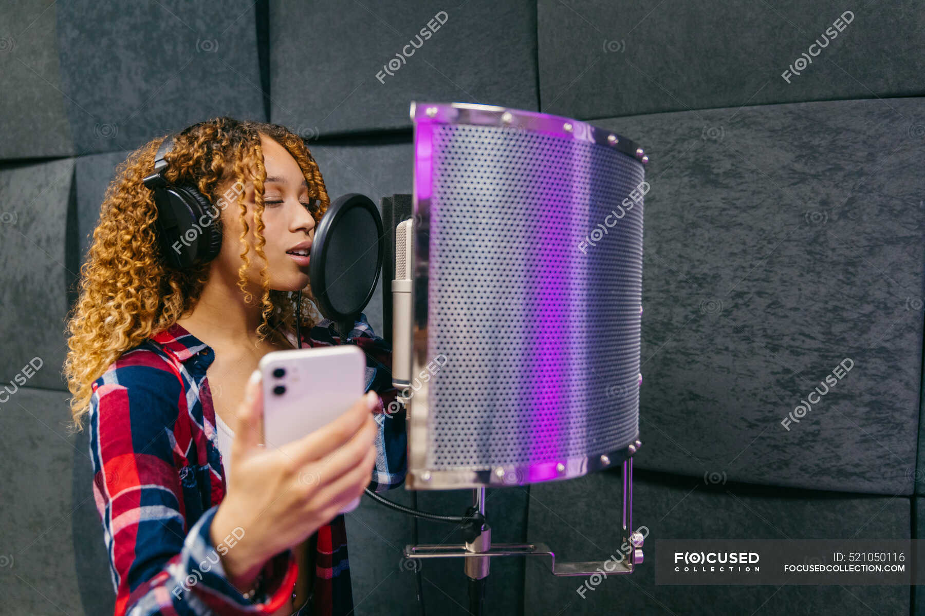 cheerful-african-american-female-singer-in-headphones-with-smartphone