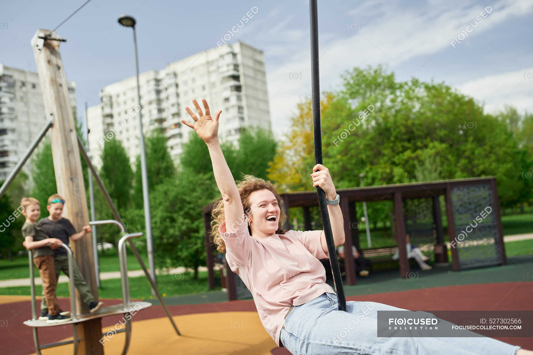 Positive female riding swing rope while laughing and having fun on