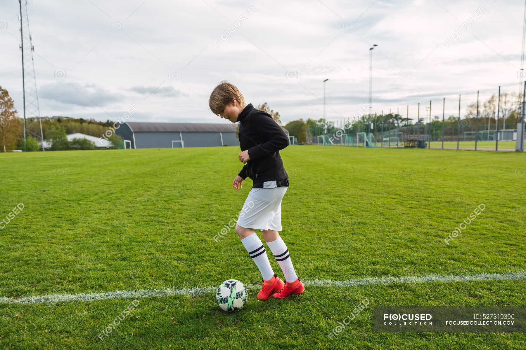 Jogadores de futebol adolescentes chutando bola de futebol campo