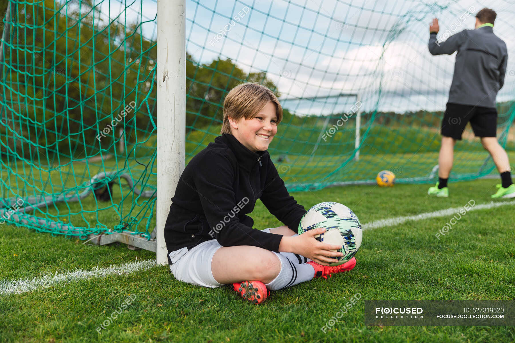 side-view-of-positive-teenage-football-player-in-activewear-sitting