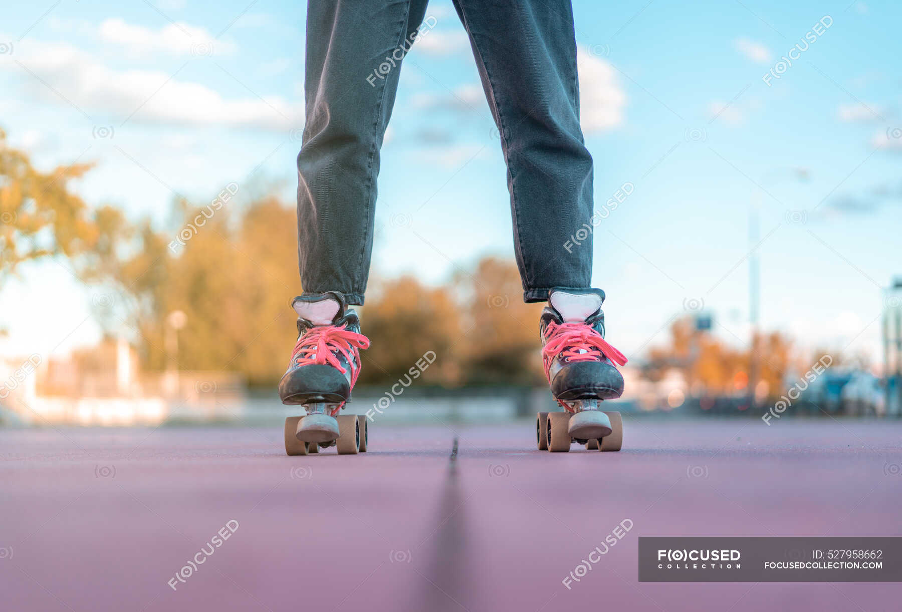 Mujer irreconocible con sudadera con rosa claro y pantalones vaqueros negros y patines con cordones de neón rosa de pie en skate park — Anónimo, Independiente - Stock #527958662