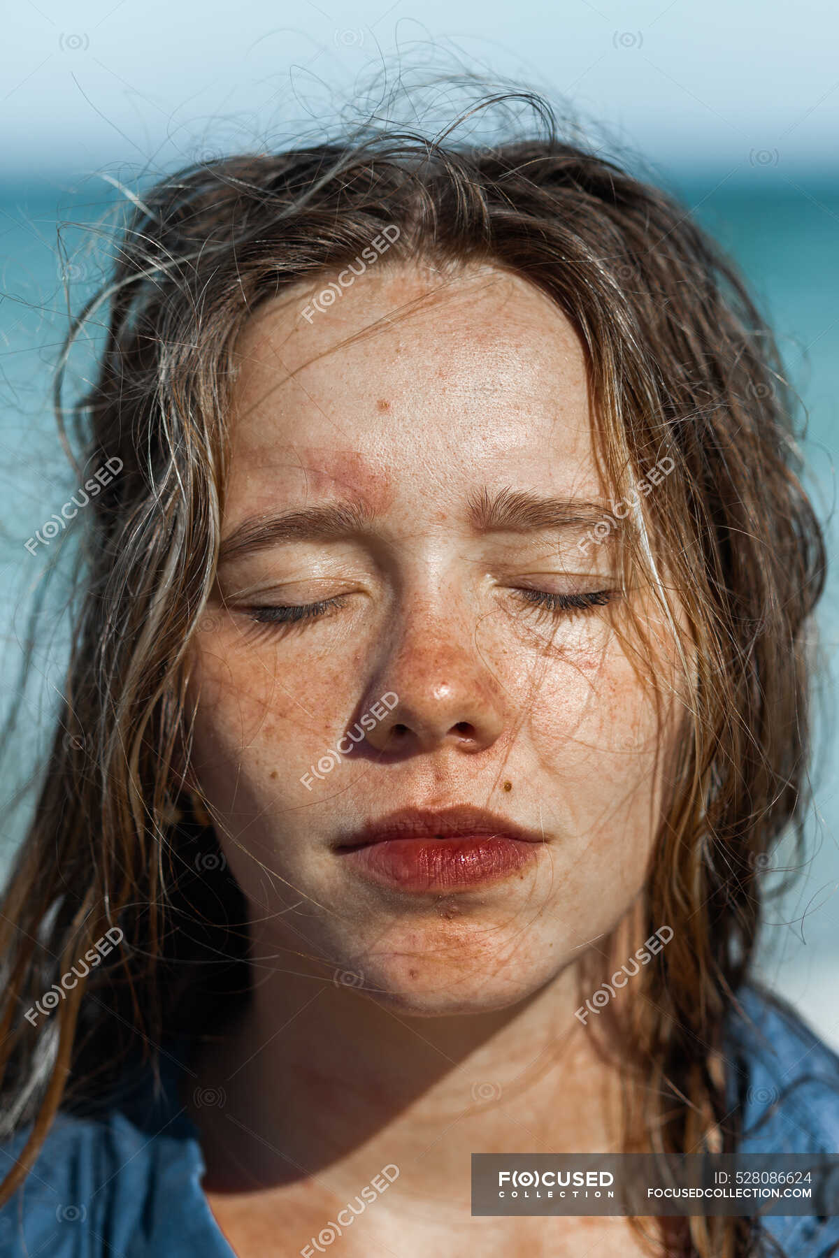 Female In Wet Shirt And With Wet Hair Standing On Beach Near Sea While