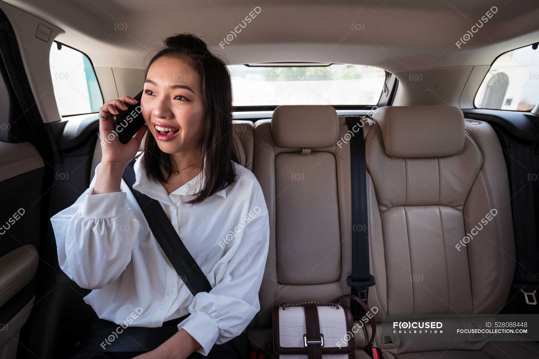 Smile ethnic female passenger with fastened seat belt talking on ...