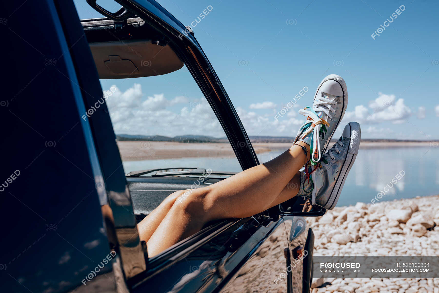 Crop unrecognizable female chilling on passenger seat in car with legs ...