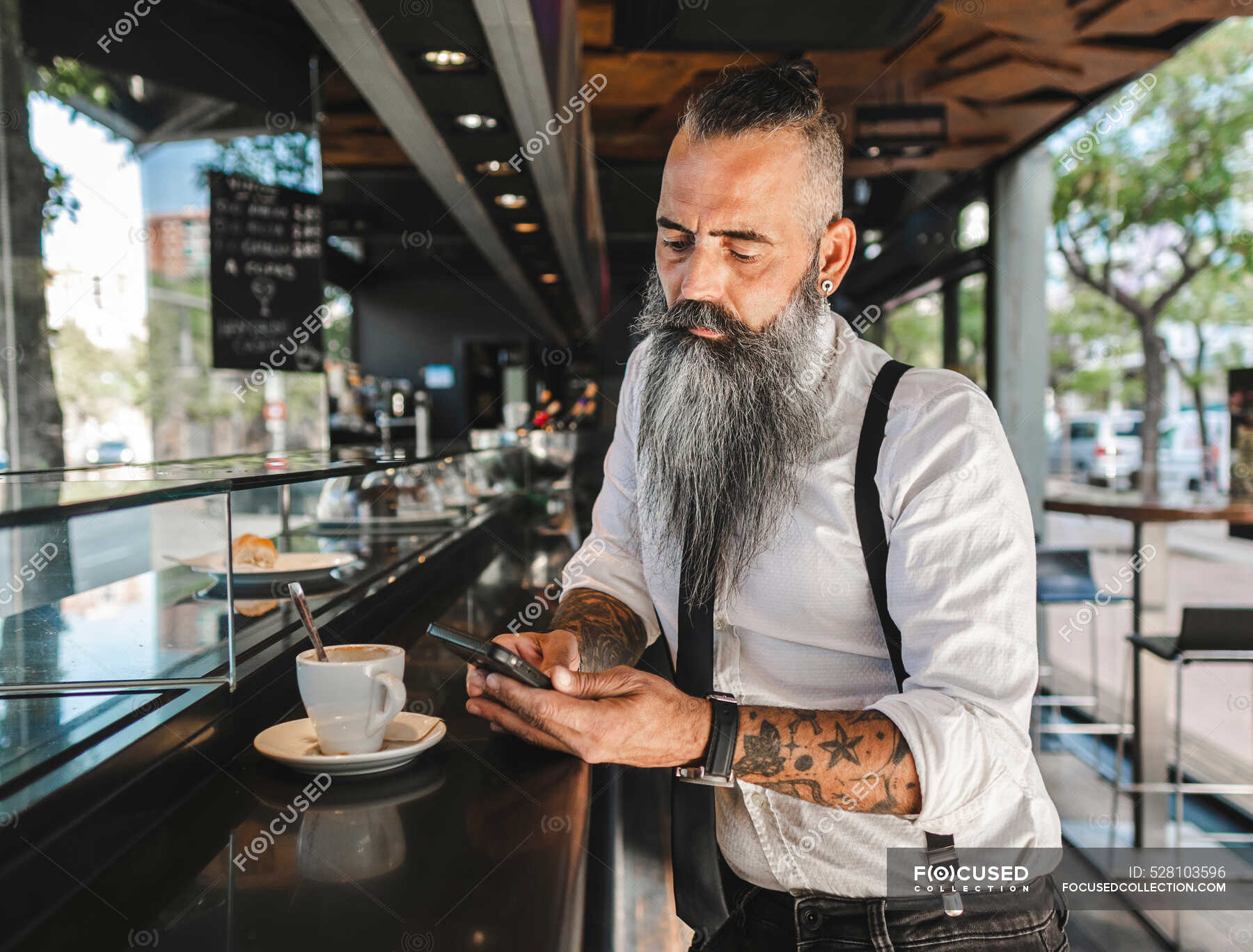 Concentrated male hipster in formal wear text messaging on cellphone while  standing near counter with cup of coffee in cafeteria — businessman,  pensive - Stock Photo | #528103596