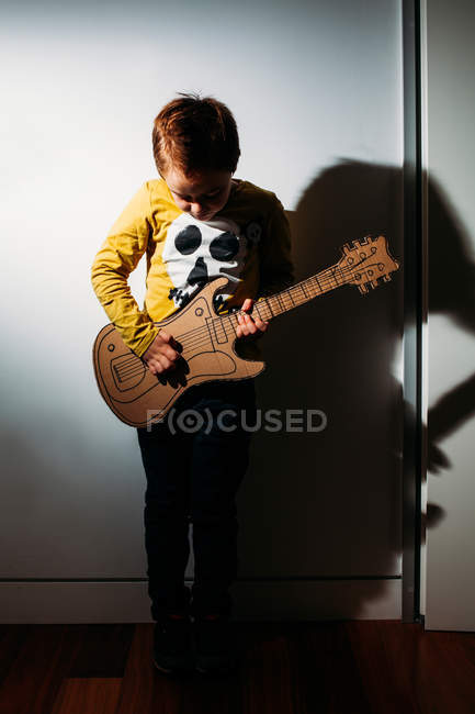 Petit garçon jouant sur la guitare jouet — Photo de stock