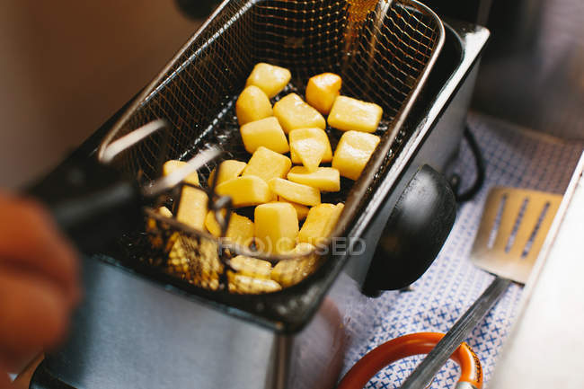 Potatoes or pieces of cheese in frying pan — Stock Photo