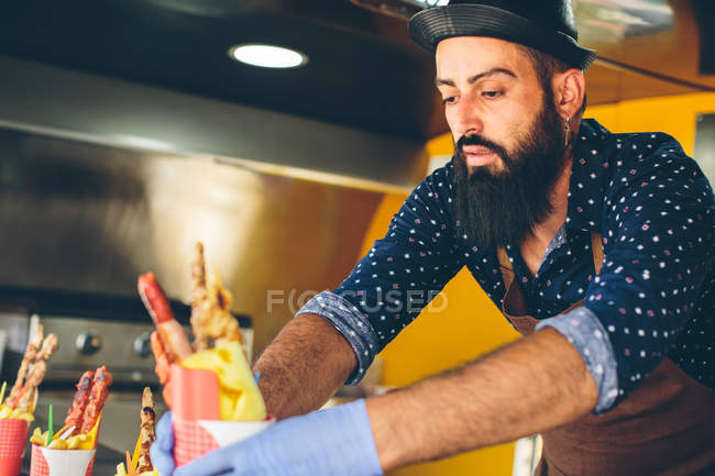 Хіпстер в капелюсі, що продає їжу в харчовій машині — стокове фото