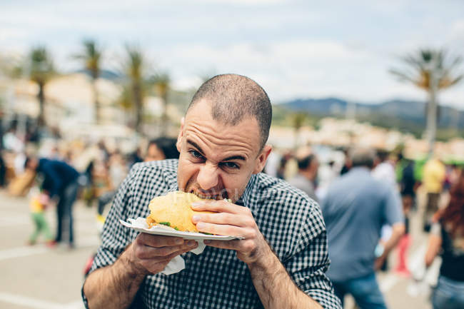 Hombre comiendo hamburguesa frita - foto de stock