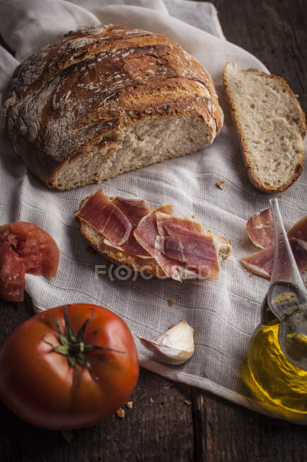 Bread and prosciutto on wooden table — Stock Photo