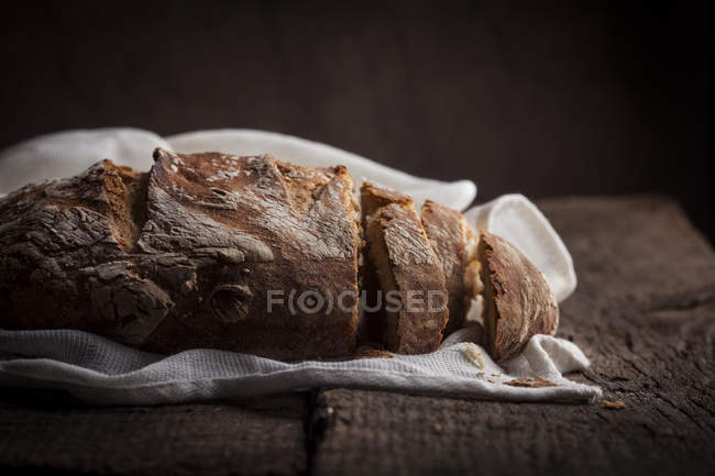 Loaf of sliced bread on white cloth — Stock Photo