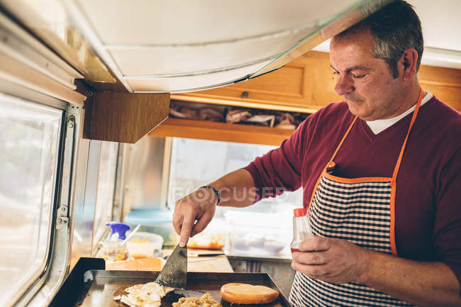 Hombre maduro cocinero preparando hamburguesa - foto de stock
