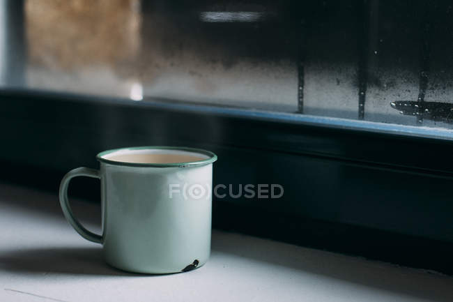 Cup of coffee on windowsill — Stock Photo