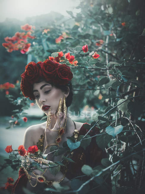 Brünette Frau mit roten Rosen auf dem Kopf — Stockfoto