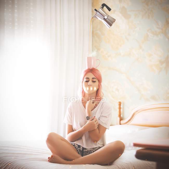 Женщина на кровати с кофе на голове — стоковое фото