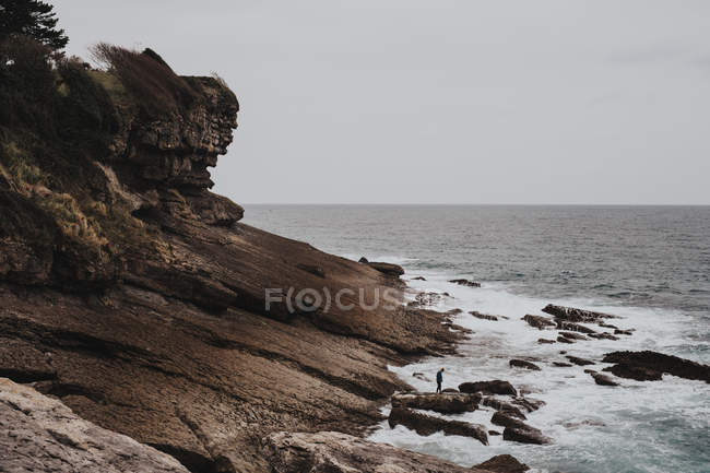 Путешественник, стоящий на скале в море — стоковое фото