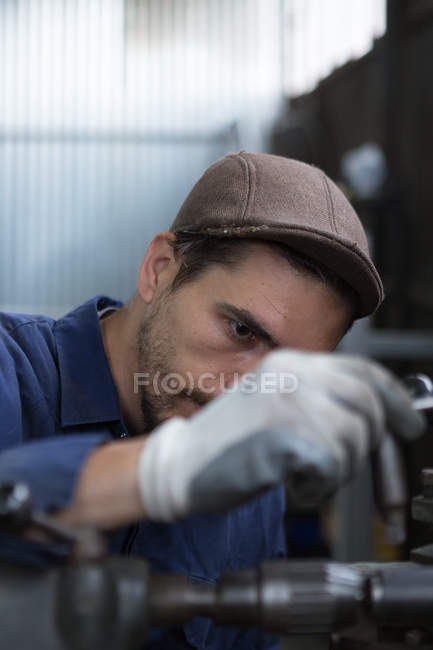 Craftsman putting metal detail in machine — Stock Photo