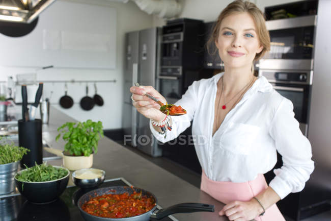 Belle femme tenant cuillère à la cuisine — Photo de stock