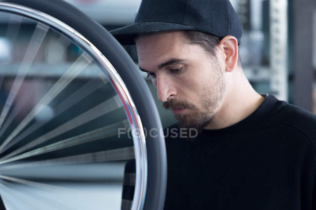 Bearded craftsman with bicycle wheel — Stock Photo