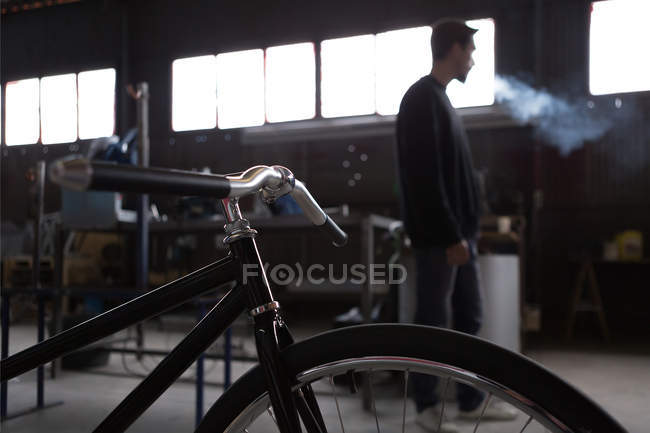 Constructed bicycle and smoking craftsman — Stock Photo