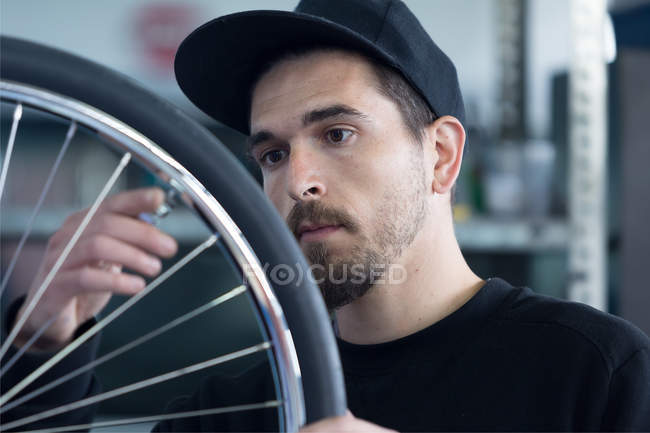 Artesano mirando rueda de bicicleta - foto de stock