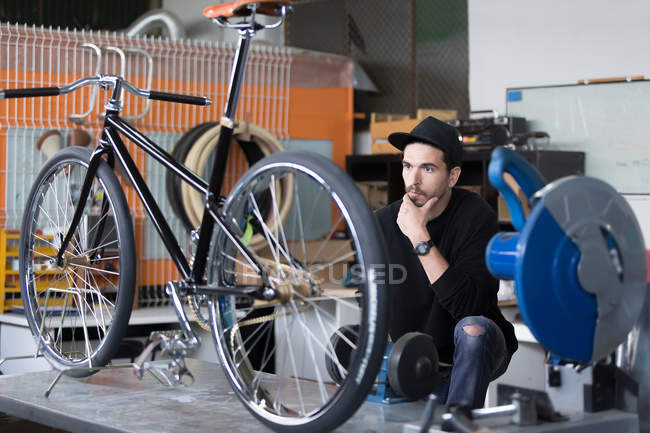 Ремесленник смотрит на велосипед в мастерской — стоковое фото