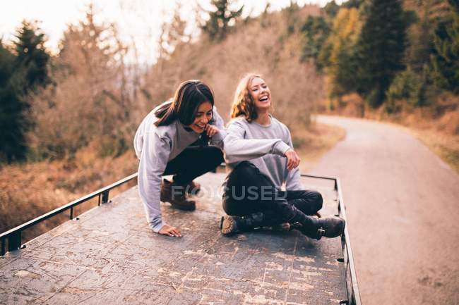 Sorridente giovani donne sul tetto dell'auto — Foto stock