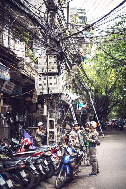 Técnico reparando red eléctrica en Hanoi - foto de stock