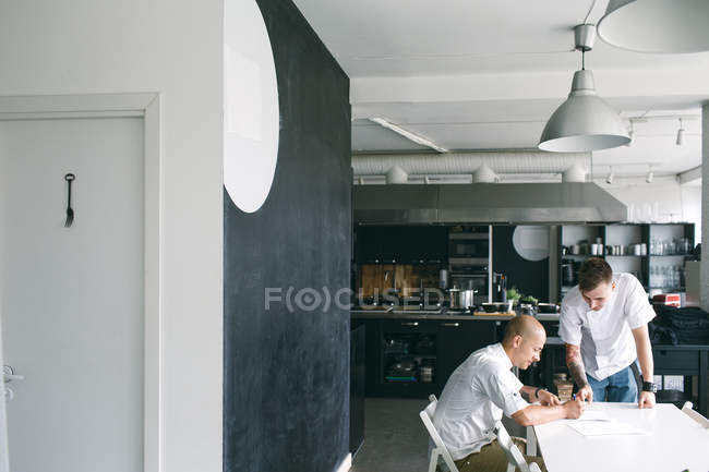 Professional cook taking notes for student — Stock Photo