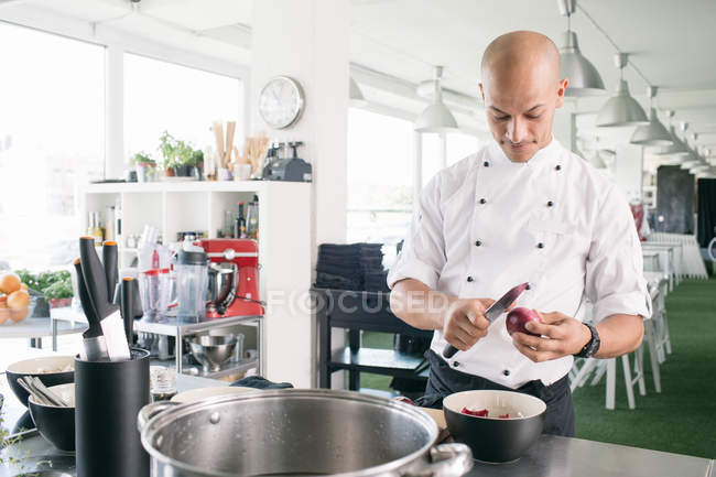 Chef cutting onion in kitchen — Stock Photo