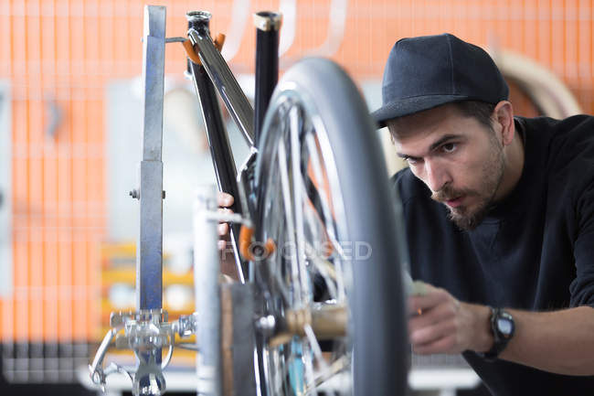 Hombre mirando rueda de bicicleta - foto de stock