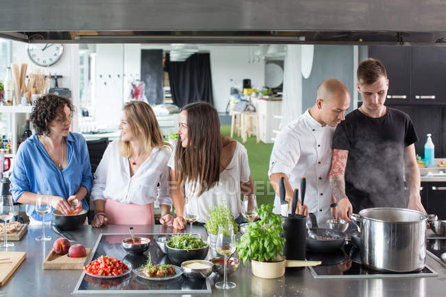 Amigos falando e cozinhando na cozinha — Fotografia de Stock