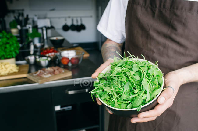 Uomo in possesso di insalata rucola in ciotola — Foto stock