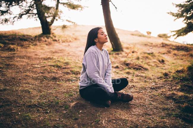 Attractive girl in lotus position at sunset — Stock Photo