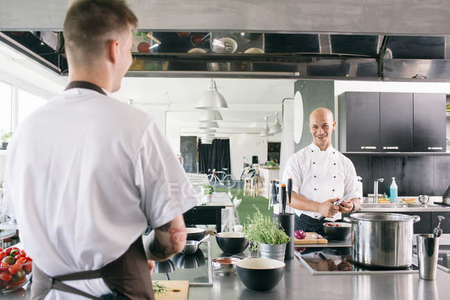 Чоловік дивиться на усміхненого шеф-кухаря на кухні — стокове фото