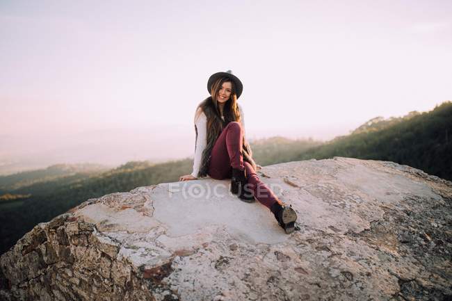 Chica sentada contra el cielo brillante - foto de stock