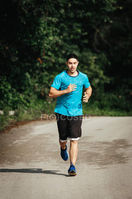 Молодий бігун вздовж асфальтової дороги — стокове фото