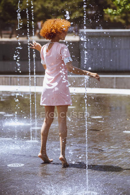 Jeune femme jouant dans la fontaine — Photo de stock