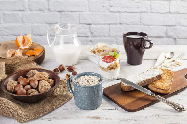 Café da manhã completo com nozes cruas, cereais, leite e frutas — Fotografia de Stock