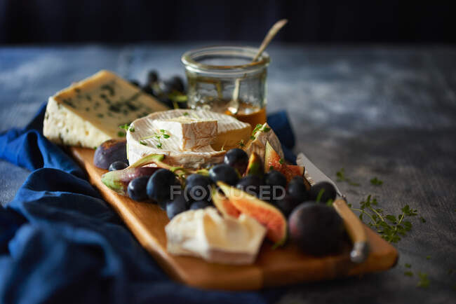 Cheese with grapes, figs on wooden board — Stock Photo