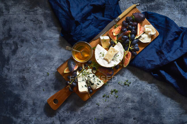 Fromage aux raisins, figues sur planche de bois — Photo de stock