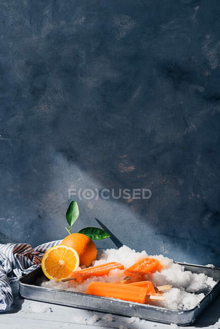 Свежие апельсины и мороженое в лотке — стоковое фото