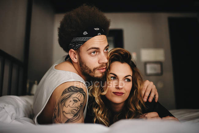 Jeune couple câlin sur le lit — Photo de stock