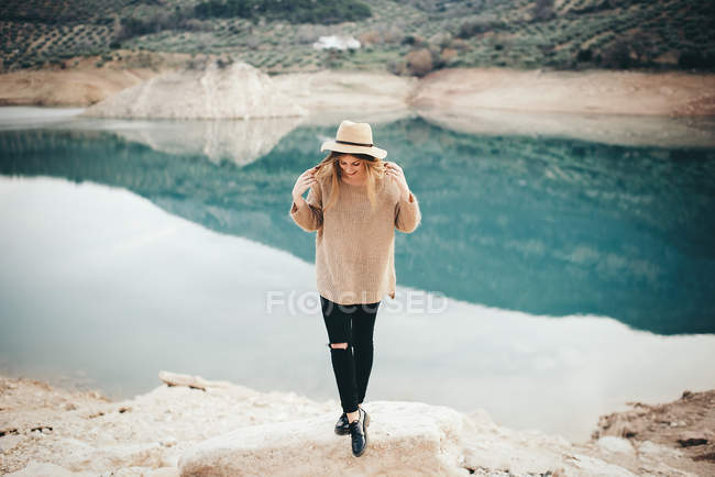 Веселая женщина в шляпе против озера — стоковое фото