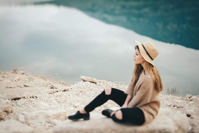 Pretty girl is sitting on stone. — Stock Photo
