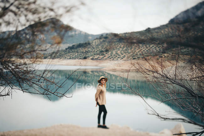 Женщина в шляпе против горного озера — стоковое фото