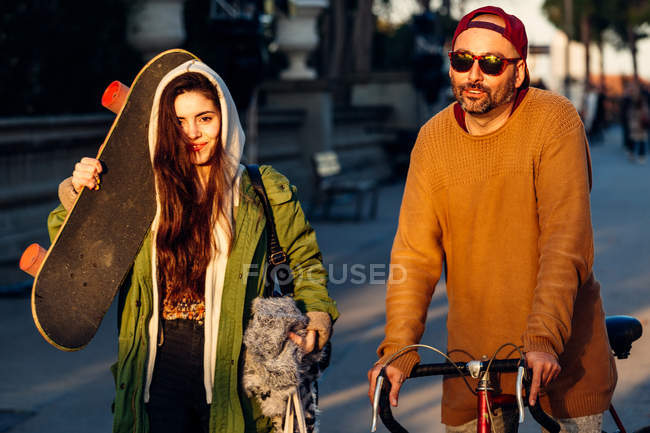 Couple tenant skateboard et vélo — Photo de stock