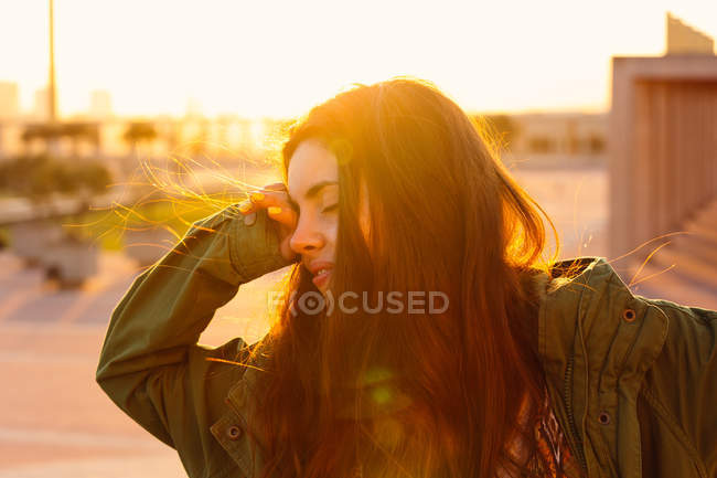 Menina morena que se estende sobre o pôr do sol — Fotografia de Stock