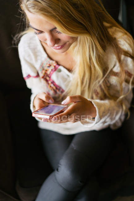 Frau benutzt Handy im Sessel — Stockfoto