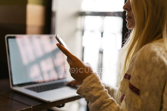 Женщина со смартфоном и ноутбуком — стоковое фото